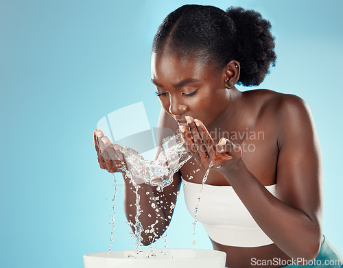 Image of Water, wash and woman splashing her face for cleansing hygiene and skincare on a blue studio background. Skin care, body care and beauty female washing her for facial health and wellness
