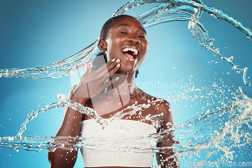 Image of Water, splash and woman washing for hygiene and grooming on a blue studio background. Young black woman wash, cleanse and cleansing body and skin for bodycare, skincare and health or wellness