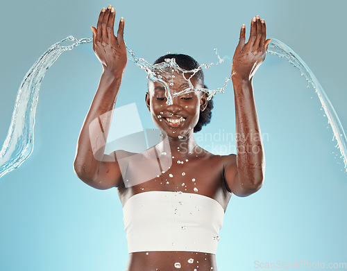 Image of Water, splash and black woman washing on a blue studio background for hygiene and grooming. Clean, cleansing and bodycare or skincare for african american female showering for beauty and wellness