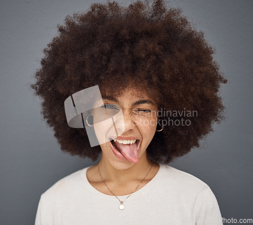 Image of Goofy, face and woman with her tongue out in studio with comic, fun and crazy facial expression. Silly, funny and portrait of happy girl model from Puerto Rico standing and posing by gray background.