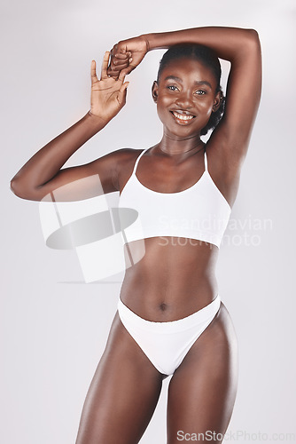 Image of Health, body and portrait of a black woman in a studio for fitness, exercise and wellness. Body care, beauty and healthy African model with a smile isolated posing by a gray background for self love.