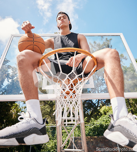 Image of Sports, basketball and man sitting on basketball hoop and preparing for training, match or competition outdoors on basketball court. Portrait, basketball player and male on rim ready for exercise.