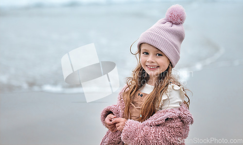 Image of Happy girl child on beach, portrait on winter holiday with pink beanie and kid smile on the Dublin seaside. Outdoor freedom on ocean break, cute toddler relaxing by the water and coastal peace