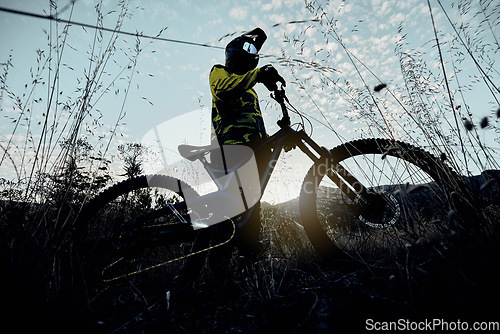 Image of Nature cycling, blue sky and man with mountain bike for cardio workout, fitness journey or travel in countryside below view. Dark shadow flare, exercise and athlete rider training for triathlon race