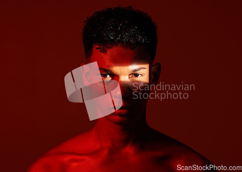 Image of Beauty, red studio and portrait of a man with with a ray of light on his face with a skincare routine. Health, spotlight and model with a wellness skin treatment isolated by a brown background.