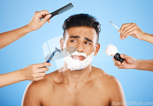 Image of Face, shave and grooming with hands holding equipment for shaving or brushing hair in studio on a blue background. Skincare, wellness and luxury with an unhappy male customer at the barber for beauty