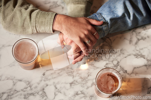 Image of Couple holding hands, above glass beer and bar with comfort, support or bonding together with drink. Helping hand, alcohol or trust with unity, love or care on countertop for empathy communication