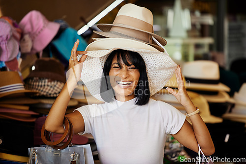 Image of Woman, hats and smile of a black woman shopping at a retail store with a comic smile. Portrait of a funny and happy sales customer laughing from luxury shop experience in a mall or clothes boutique