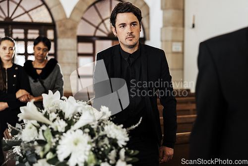 Image of Funeral, death and grief with a man pallbearer carrying a coffin in a church during a ceremony. Flowers, suit and loss with a male holding a casket while walking through a chapel for mourning