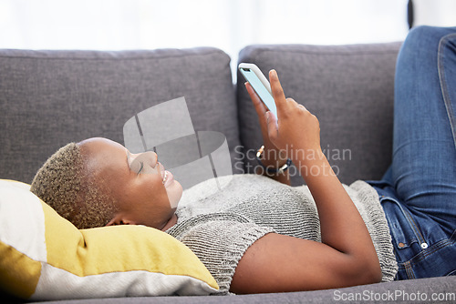 Image of Black woman with smartphone, social media and technology with communication and relax on sofa at home. Internet, connection and young person chatting or email, streaming online or funny meme.