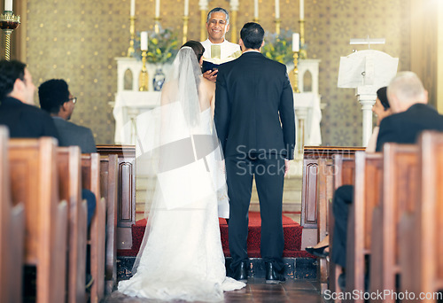 Image of Wedding, priest and couple at the altar for marriage vows in commitment ceremony in a church from behind. Married, love and caring bride and groom celebrating their loving relationship in a chapel