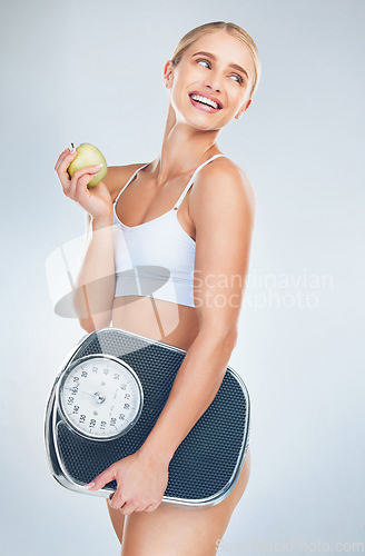Image of Apple, diet and woman with scale for body health, self care and natural weight loss. Eating healthy food, nutrition lifestyle and wellness exercise training for fat workout in gray studio background