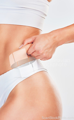 Image of Hand, pinch and woman in underwear her belly fat for weight loss on a white studio background. Overweight, cellulite and fat with a woman with a healthy lifestyle and diet for stomach loss