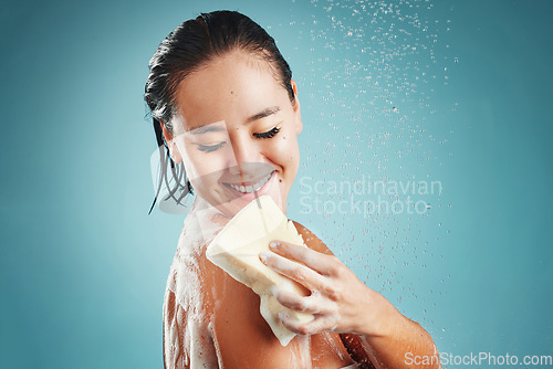 Image of Studio, skincare and woman in shower with sponge isolated on a blue background mockup. Water splash, cleaning or healthy hygiene of female model bathing, washing or showering for beauty and body care