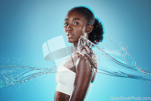 Image of Skincare, water and black woman with a splash for hydration, cleaning and beauty against a blue studio background. Spa, wellness and African model with peace, calm and relax from liquid bodycare