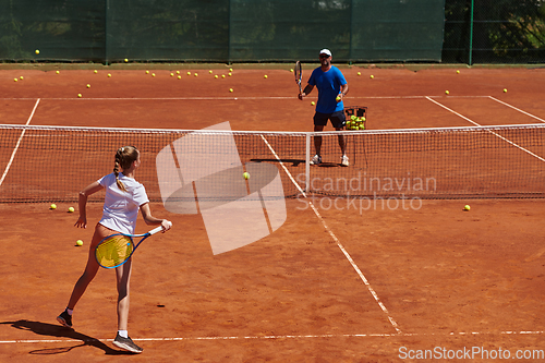 Image of A professional tennis player and her coach training on a sunny day at the tennis court. Training and preparation of a professional tennis player