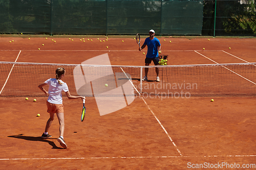 Image of A professional tennis player and her coach training on a sunny day at the tennis court. Training and preparation of a professional tennis player