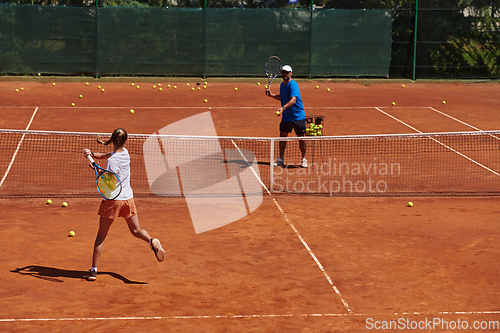 Image of A professional tennis player and her coach training on a sunny day at the tennis court. Training and preparation of a professional tennis player