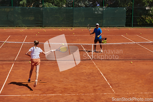 Image of A professional tennis player and her coach training on a sunny day at the tennis court. Training and preparation of a professional tennis player