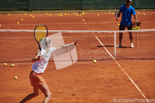 Image of A professional tennis player and her coach training on a sunny day at the tennis court. Training and preparation of a professional tennis player