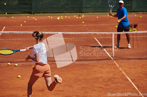 Image of A professional tennis player and her coach training on a sunny day at the tennis court. Training and preparation of a professional tennis player