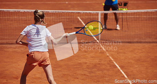 Image of A professional tennis player and her coach training on a sunny day at the tennis court. Training and preparation of a professional tennis player