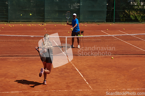 Image of A professional tennis player and her coach training on a sunny day at the tennis court. Training and preparation of a professional tennis player