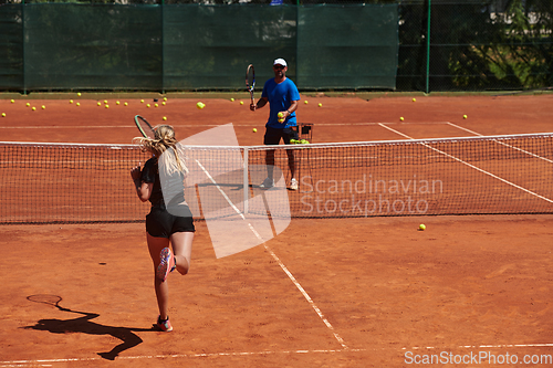 Image of A professional tennis player and her coach training on a sunny day at the tennis court. Training and preparation of a professional tennis player