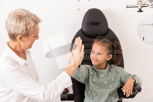 Image of High five, optometrist and children with a girl and woman in an optometry appointment for prescription lenses. Motivation, eye test and success with a female child and optician in celebration