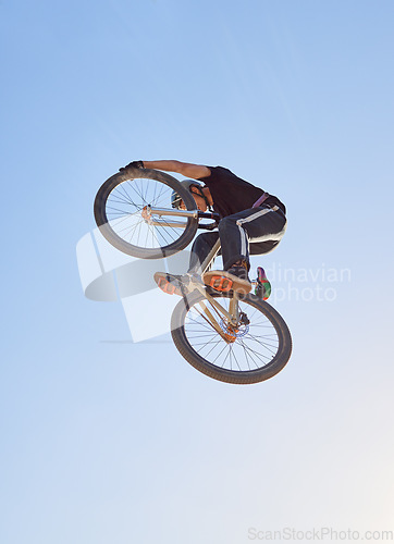 Image of Mountain bike, speed and sports with a man jumping in the air during a race outdoor against the sky from below. Blue sky, energy and bicycle with a professional male biker or athlete in action