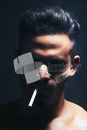 Image of Cigarette, boxer and man with fighting injury, wound and bandaid after fight, violence or accident in a dark studio. Portrait of fighter, shadow or gangster smoking after MMA match or crime