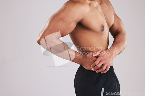 Image of Pain, waist and man with an injury after exercise, fitness and training against a grey studio background. Healthcare, accident and person feeling their body with appendicitis and medical emergency