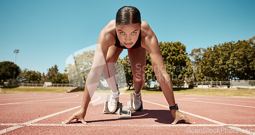 Image of Sports, running and fitness with a woman athlete starting a race on a track for competitive training or exercise. Health, workout and energy with a young female runner at a sport stadium for cardio