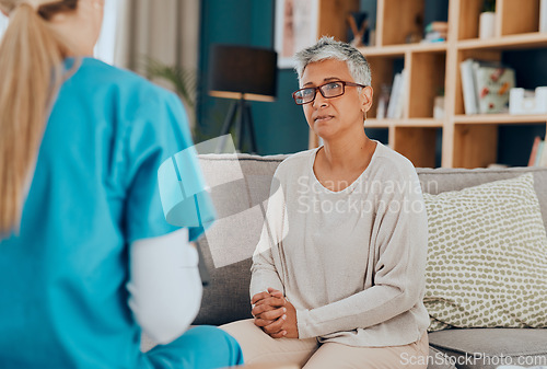 Image of Nurse, senior woman and consultation on sofa in home for health check up or examination. Healthcare, consulting and female doctor with elderly patient in living room discussing treatment options.