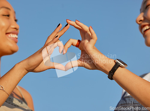 Image of Heart, love and friends with a sign of their support, trust and happy against a blue sky. Nature, care and women with emoji hands for travel natural environment and wellness in summer together