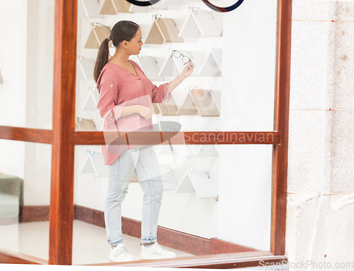 Image of Shopping, retail and woman with glasses at a store for quality choices, frames on promotion and eye care. Decision, girl or customer checking options for better eyesight or clear vision at optician