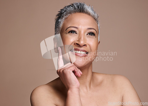 Image of Face, beauty and skincare with a mature model woman in studio on a brown background thinking about wellness. Luxury, cosmetics and antiaging with a senior female posing to promote a skin product