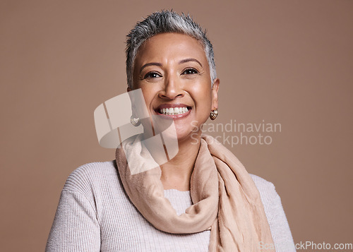 Image of Face, fashion and beauty with a senior woman in studio on a brown background to promote contemporary style. Portait, fashionable and trendy with a mature female posing to model a clothes brand