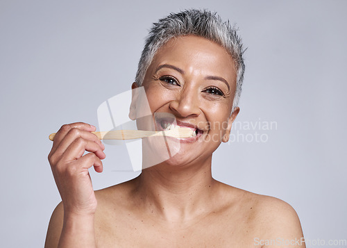 Image of Mature woman, toothbrush and brushing teeth on studio background, morning grooming routine or healthcare wellness. Portrait, smile or beauty model in dental care cleaning or happy hygiene maintenance