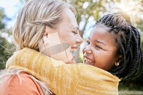 Image of Happy family, love and interracial mother and girl hug at a park, happy and relax while bonding, laughing and having fun in nature. Adoption, foster and woman with black child, hug and joy