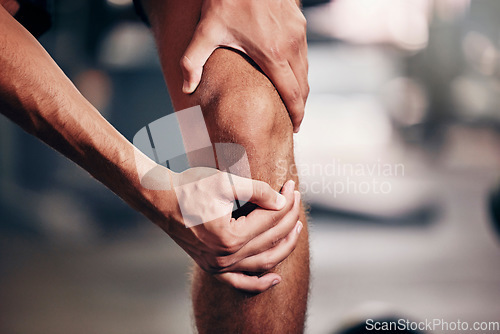 Image of Fitness, exercise and man with knee pain in the gym, closeup of hands holding knee after injury. Sports, health and hurt male athlete with sore joint in leg after workout, training and exercising