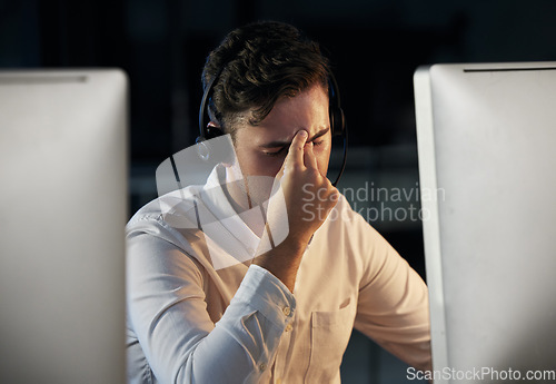 Image of Call center, telemarketing and man with headache and stress working overtime at night. Burnout, tired and frustrated male consultant sitting in office for crm, customer support and customer service