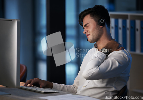 Image of Call center, neck pain and business man at night with burnout, stress and fatigue at office desktop computer consulting. Telemarketing or salesman consultant with shoulder pain or health risk problem