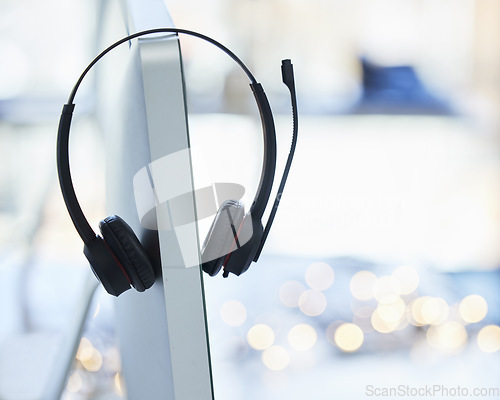 Image of Headphones, computer and call center desk in office for telemarketing employee equipment. Contact us, tech gadget and audio support tools for help desk customer service worker on desktop monitor