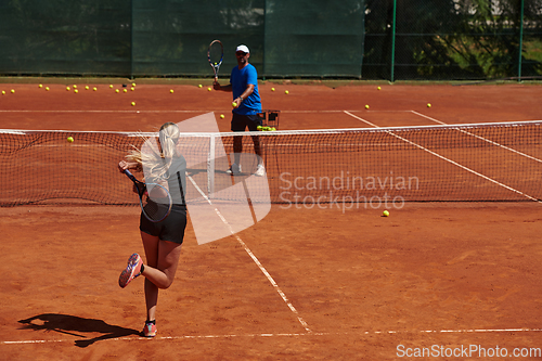 Image of A professional tennis player and her coach training on a sunny day at the tennis court. Training and preparation of a professional tennis player