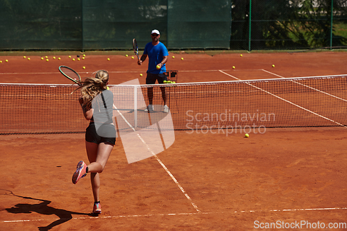 Image of A professional tennis player and her coach training on a sunny day at the tennis court. Training and preparation of a professional tennis player