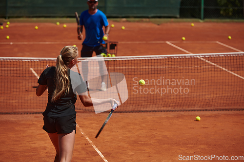 Image of A professional tennis player and her coach training on a sunny day at the tennis court. Training and preparation of a professional tennis player