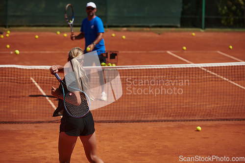 Image of A professional tennis player and her coach training on a sunny day at the tennis court. Training and preparation of a professional tennis player