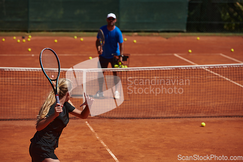 Image of A professional tennis player and her coach training on a sunny day at the tennis court. Training and preparation of a professional tennis player