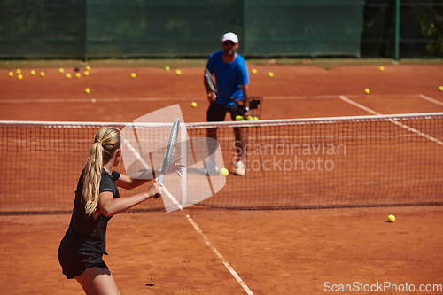 Image of A professional tennis player and her coach training on a sunny day at the tennis court. Training and preparation of a professional tennis player